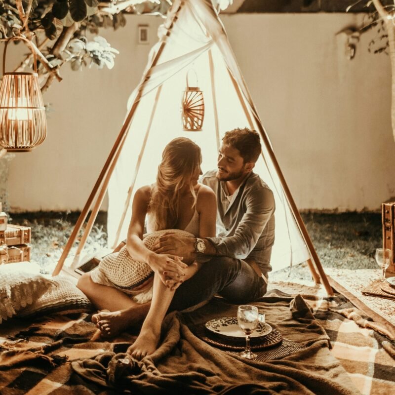 couple sitting inside tepee hut with lights